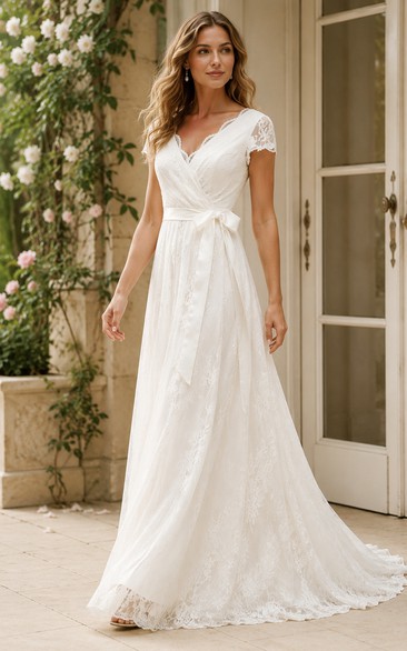 Robe de mariée en dentelle, coupe trapèze, décolleté en V festonné, manches courtes illusion, longueur au sol