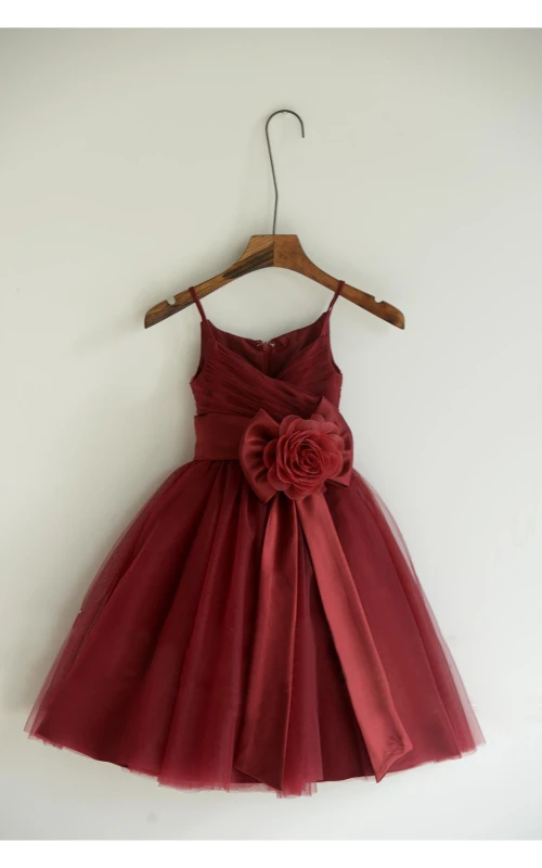 Robe longue en tulle plissée, coupe trapèze, bustier croisé et fines bretelles spaghetti, ornée d'une fleur