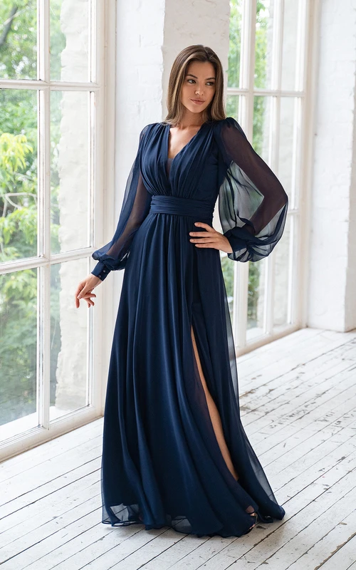 Vestido largo de gasa con escote en V, mangas largas ilusión y corte imperio, con abertura frontal.