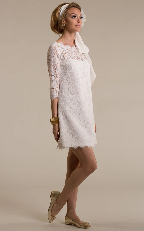 Robe de mariée fourreau courte en dentelle à manches 3-4 et décolleté rond, ornée d'appliqués et dos en V.