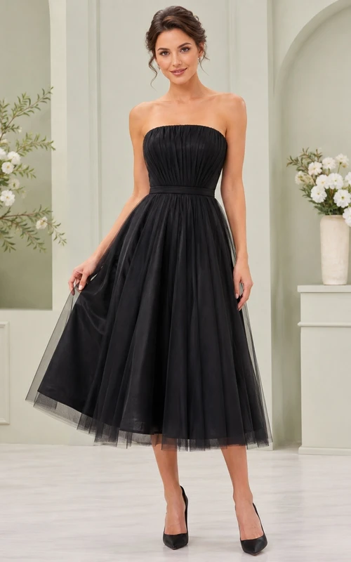 Vestido negro de tul sin tirantes, sin mangas, de corte A, largo hasta la rodilla, con pliegues.