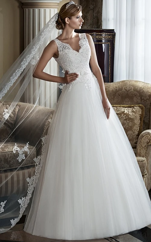 Robe de mariée longue sans manches en tulle et dentelle, coupe trapèze, col en V et applications.