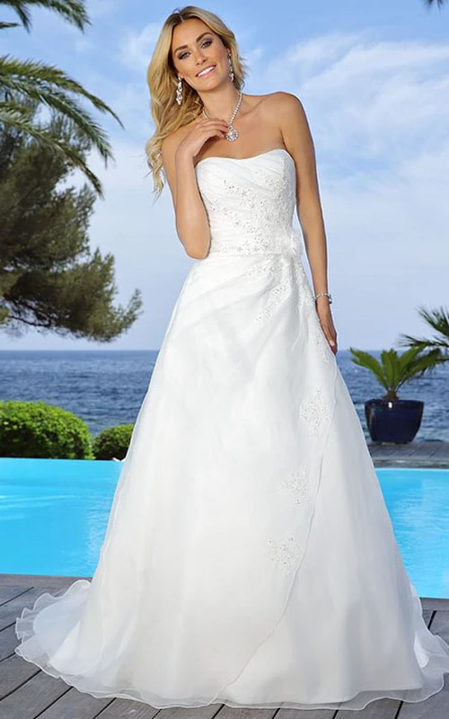 Robe de mariée bustier longue en satin drapé ornée d'appliqués, de fleurs et d'une cape