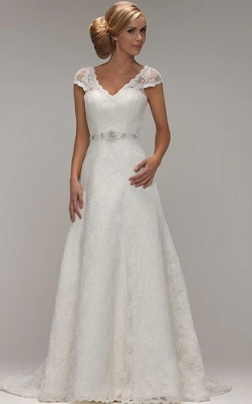 Robe de mariée en dentelle ornée de bijoux, coupe trapèze, col en V, manches courtes et dos en V.
