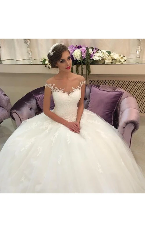 Elegante vestido de novia de tul con hombros descubiertos y apliques de encaje.