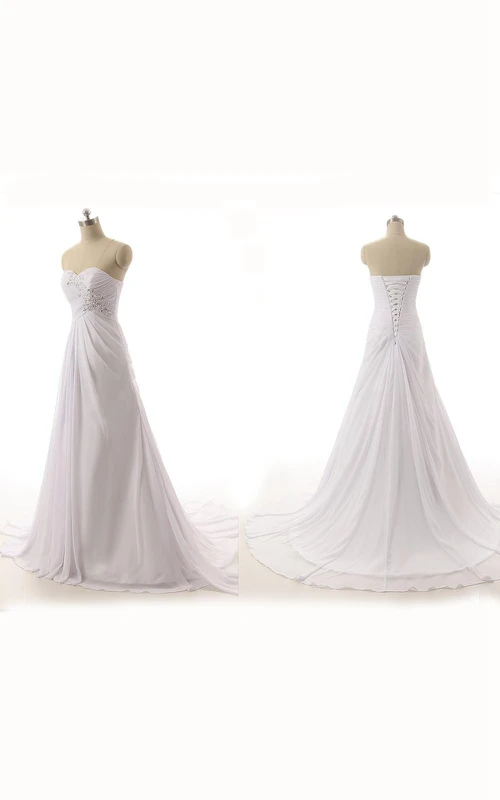 Robe longue trapèze en mousseline et dentelle, sans manches, décolleté cœur et appliques en forme de cloche au dos.