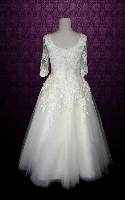 Robe de mariée en tulle mi-longue à col en V, manches mi-longues et dos nu en V, ornée d'une ceinture et d'appliques.