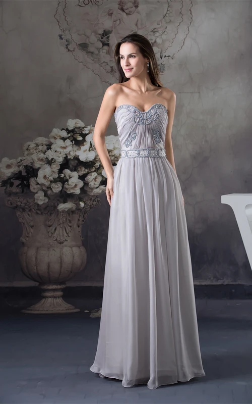 Vestido largo de gasa con escote corazón, fruncido y detalles de pedrería.