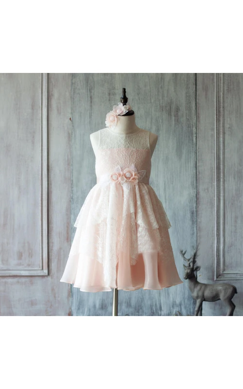 Robe de soirée sans manches à col bateau illusion, coupe trapèze, en dentelle superposée avec ceinture fleurie.