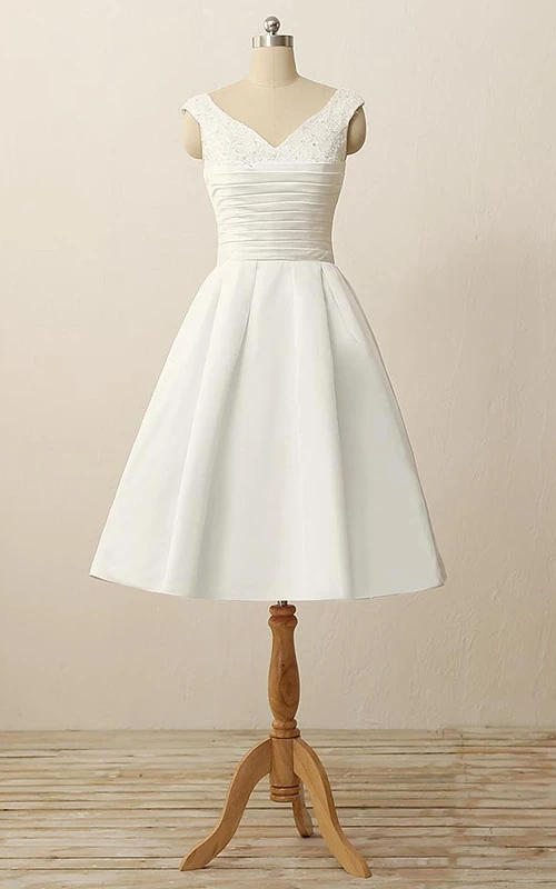 Vestido corto de satén con escote en V, pliegues, apliques de cuentas y detalles de pedrería.