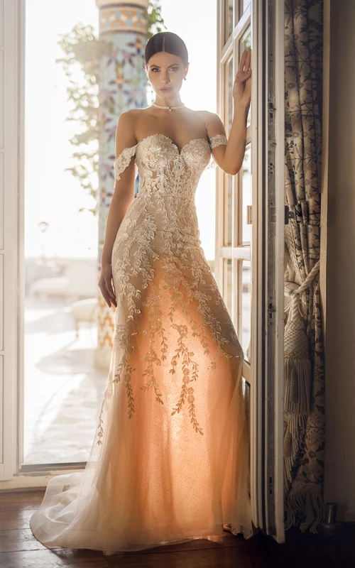 Robe de mariée fourreau en dentelle organza, décolleté cœur, épaules dénudées, longueur au sol, ornée d'appliqués et jupe amovible.