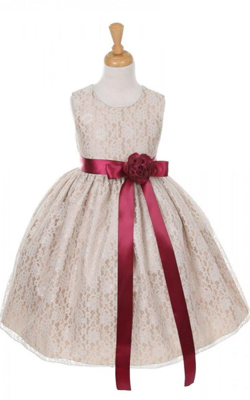 Robe en dentelle sans manches à encolure ronde et coupe trapèze, ornée d'une fleur et d'un nœud.