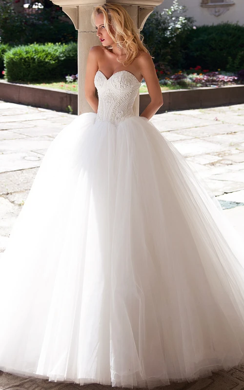 Vestido de novia de gala largo hasta el suelo con escote corazón y tul sin mangas, adornado con cuentas.