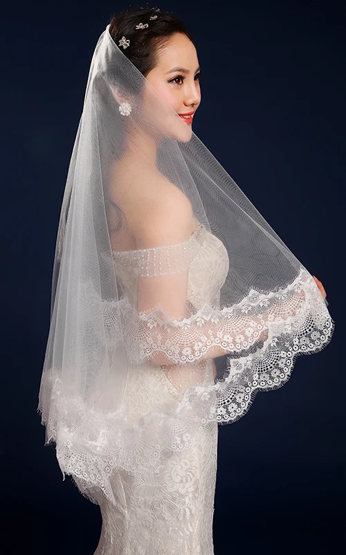 Voile de mariée en tulle bordé de dentelle, longueur bout des doigts.