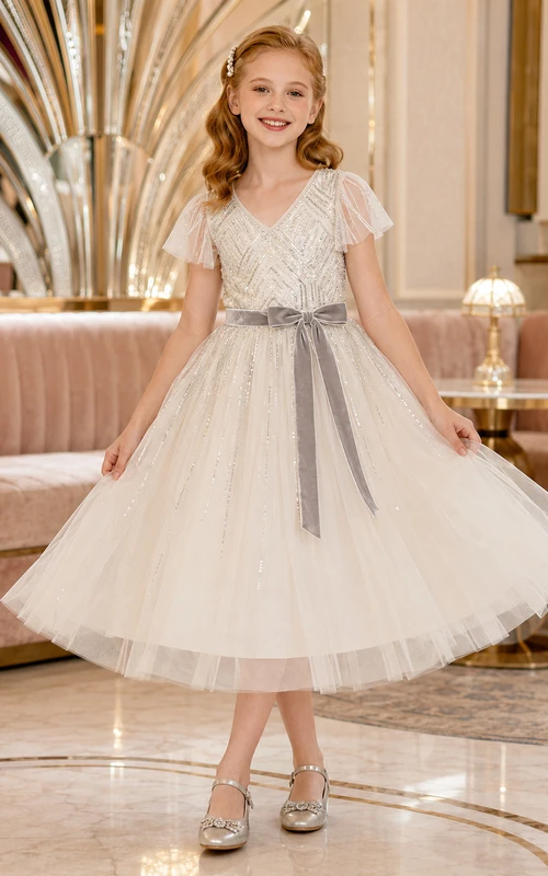 Vestido de niña de flores color marfil, largo hasta la rodilla, tul con lentejuelas, corte en A, escote en V, mangas con volantes, abalorios geométricos plateados, lazo de terciopelo gris.