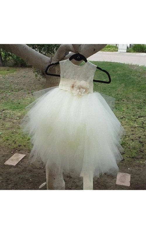 Robe de bal en tulle à plusieurs épaisseurs, décolleté rond, ornée d'une fleur à la taille.
