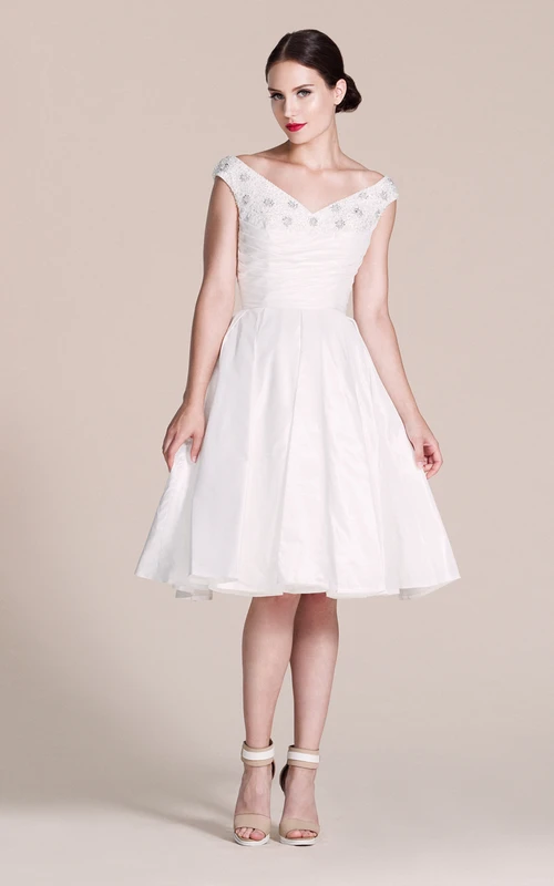 Vestido de corte A hasta la rodilla con hombros descubiertos y detalles de pedrería.