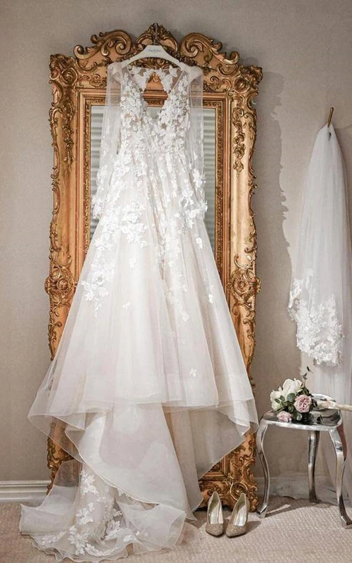 Vestido de novia de corte A con escote en V, mangas largas, efecto ilusión y apliques de encaje.