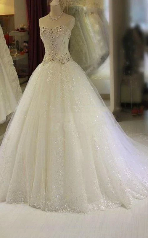 Robe de mariée princesse glamour en tulle à décolleté cœur orné de cristaux et de strass, avec traîne