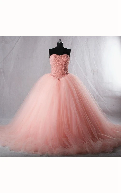 Robe en tulle et dentelle à bretelles mi-longues, décolleté en cœur, plis cloche, perles et volants, fermeture éclair et bretelles corset au dos.