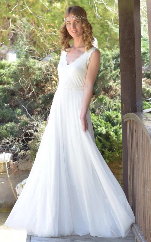 Robe de mariée en mousseline de soie et dentelle sans manches, décolleté plongeant, ornée d'un nœud et d'un dos en V profond.