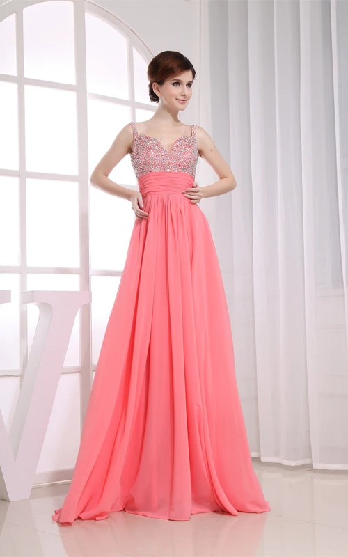Vestido largo de gasa con tirantes finos, pedrería y pliegues.
