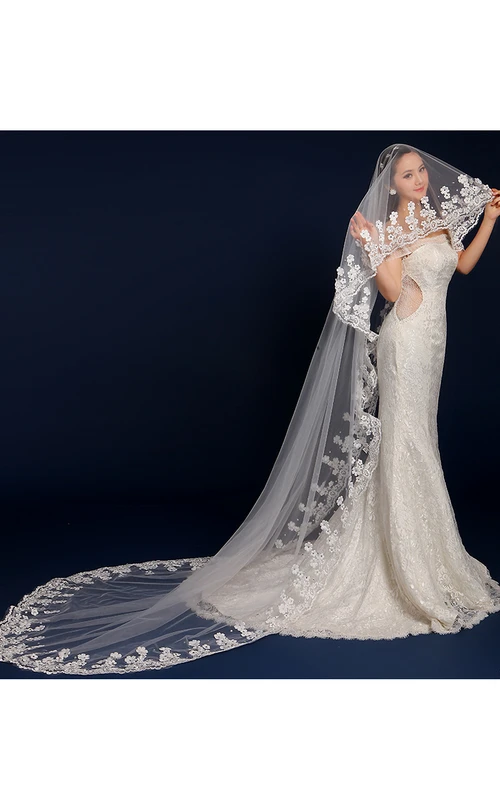 Voile de mariée à longue traîne orné de fleurs, de perles et de dentelle.