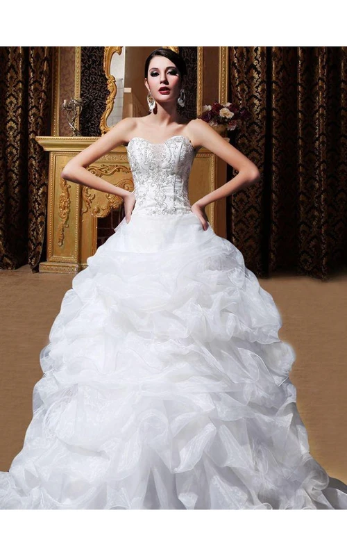 Vestido de novia de organza estilo princesa con escote corazón, bordados y cola de capilla con volantes.