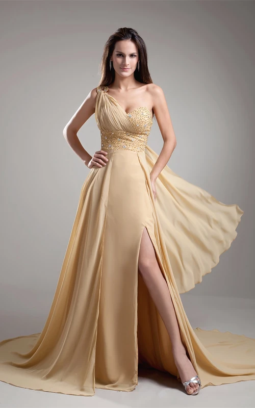 Vestido largo asimétrico con abertura frontal y parte superior adornada con joyas.