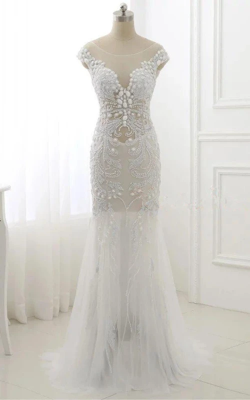 Vestido de tul con mangas cortas estilo trompeta, adornado con cuentas y lentejuelas.
