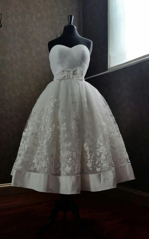 Robe de première communion en organza et dentelle, coupe trapèze, longueur thé, décolleté cœur, avec nœud.