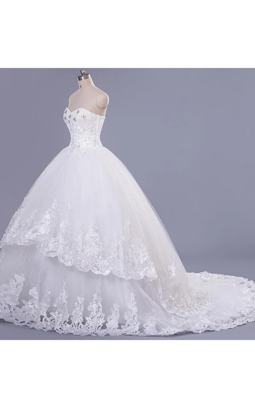 Robe de mariée moderne en tulle et dentelle, décolleté cœur sans manches, ornée de perles et de lacets.