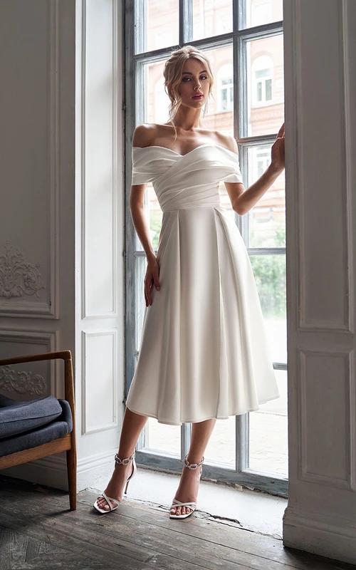 Vestido de novia de corte imperio, largo hasta la rodilla, con escote Bardot, fruncido y tiras cruzadas.