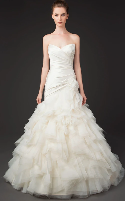 Vestido de novia de tul estilo sirena con escote corazón, volantes cruzados y en cascada.
