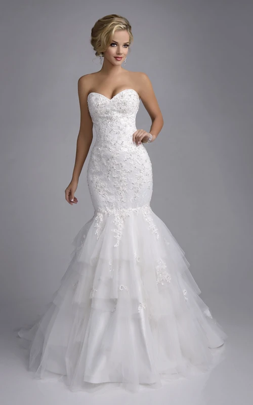 Vestido de novia de encaje y tul estilo sirena con escote corazón y falda de capas.