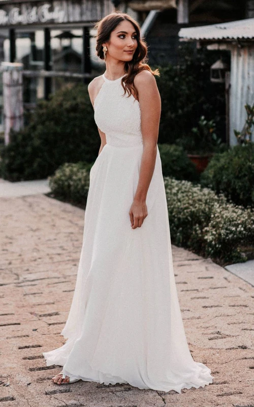 Vestido de novia bohemio de corte A, escote halter, encaje y gasa, largo hasta el suelo y con espalda descubierta.