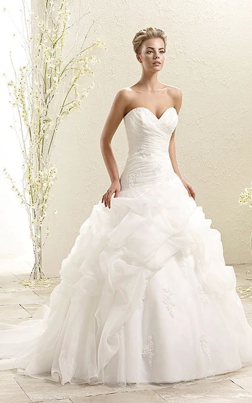 Robe de bal en organza, bustier cœur à volants, longueur au sol, ornée de bretelles croisées et d'appliques.