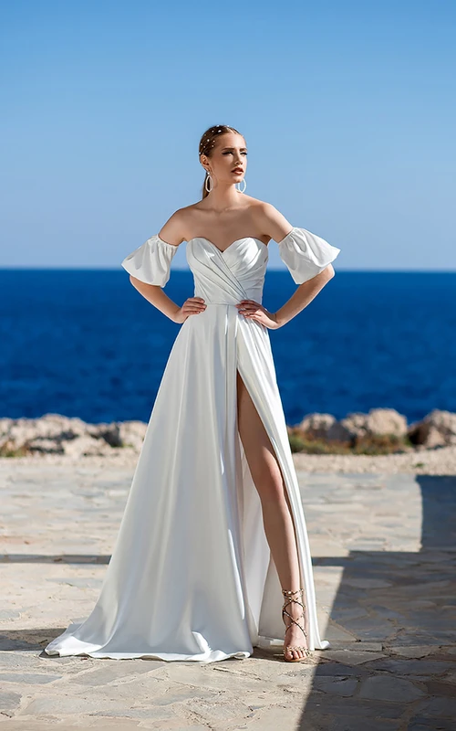 Robe de mariée de plage en satin, coupe trapèze, décolleté cœur, manches courtes, traîne, fente sur le devant et corset au dos.