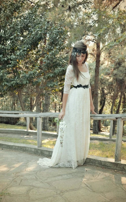 Vestido de novia bohemio de encaje con escote redondo, mangas de media ilusión, fajín y espalda abotonada.