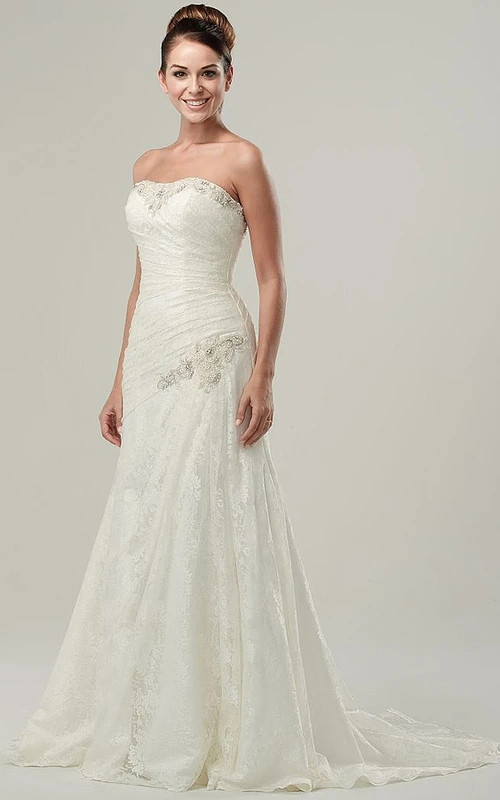 Robe de mariée en dentelle sans manches, sans bretelles, de coupe trapèze, longue jusqu'au sol, ornée de perles, avec drapé latéral et appliques.
