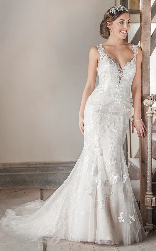 Robe de mariée longue à bretelles, ornée d'appliqués en tulle et dentelle, avec traîne courte et effet illusion.