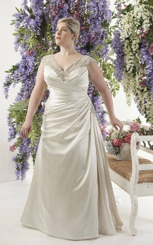 Vestido de satén con fruncido lateral y mangas tipo capa, con espalda de encaje transparente.