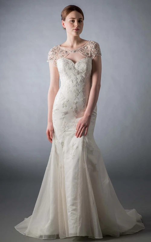 Vestido de novia de sirena con escote redondo, mangas cortas, tul y encaje con cuentas y abertura en forma de ojo de cerradura.