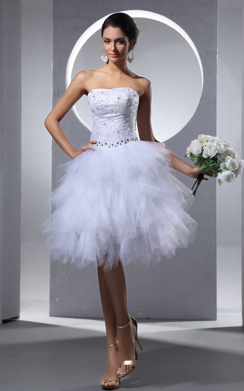 Robe courte bustier arrivant au genou, ornée de perles et de volants