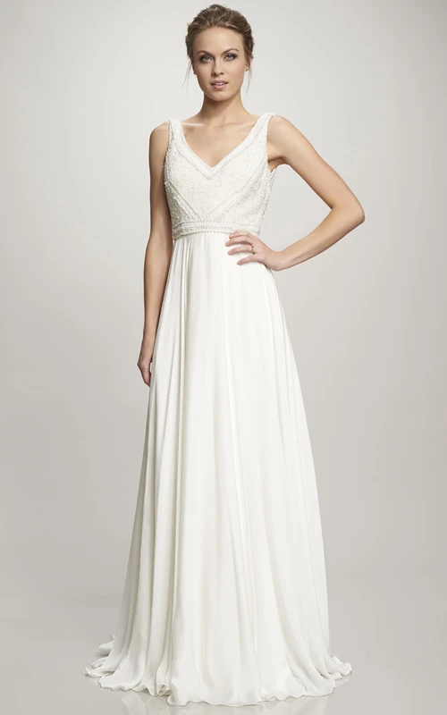 Vestido de novia largo de gasa con escote en V, bordados, cola y espalda en V.