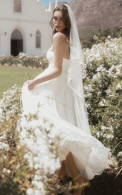 Adorable vestido de novia de tul sin mangas con escote corazón, corte en A, apliques y volantes.