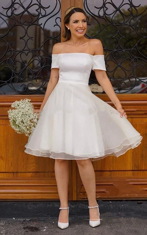 Robe de mariée vintage en organza satiné, coupe trapèze, sans manches, arrivant au genou et ornée de plis