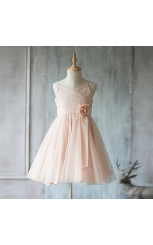 Robe courte en tulle plissé à fines bretelles et col en V, coupe trapèze, ornée d'une fleur.