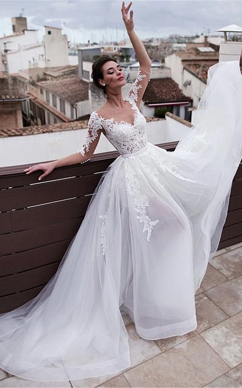 Vestido de novia de encaje fluido con mangas cortas, apliques de tul y cola desmontable.