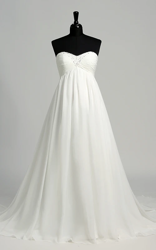 Robe de mariée en mousseline de soie, coupe trapèze, décolleté cœur sans manches, longueur au sol, avec traîne courte.